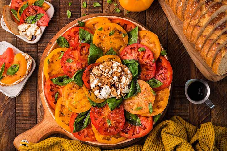 An overhead view of a platter filled with heirloom Italian burrata caprese salad.