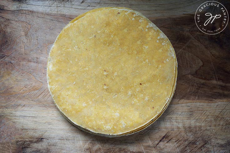 A stack of corn tortillas laying on a cutting board.