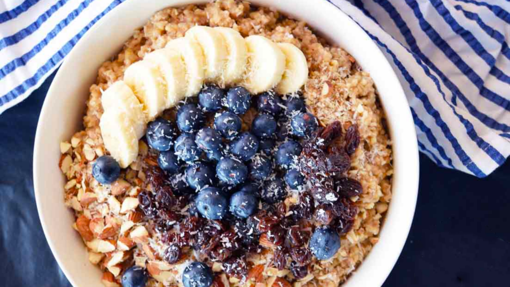 An overhead view looking down into a bowl filled with instant pot superfood oatmeal. Bananas, blueberries, raisins and almonds lay over the top of the oats.