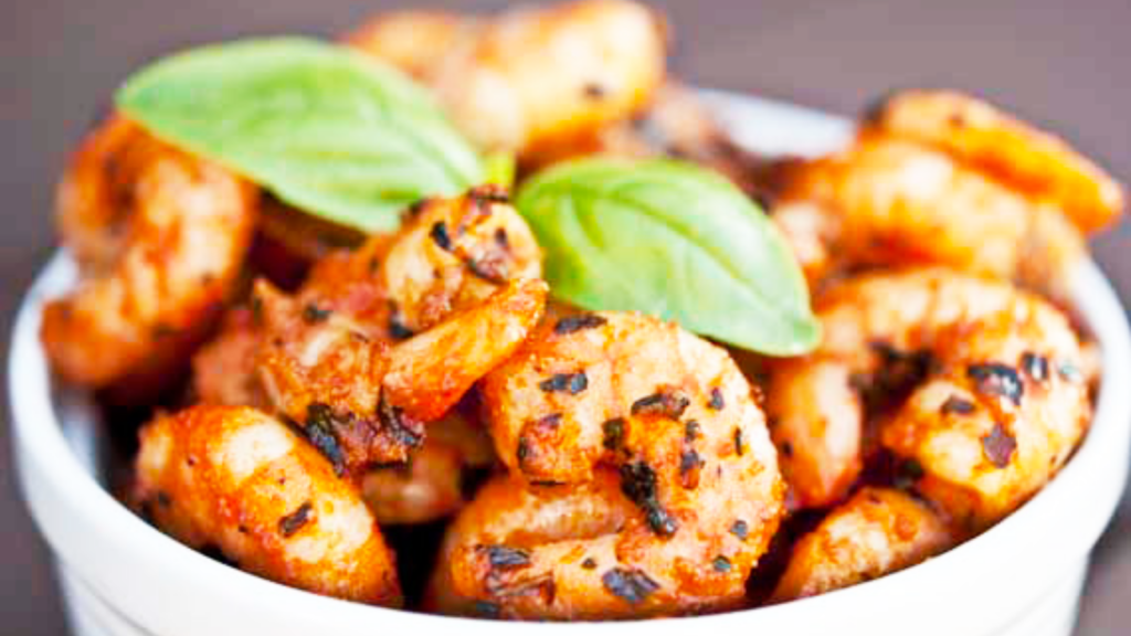 A side view of a white bowl filled with Italian shrimp.