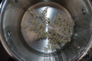 Lavender flowers in water in a pot on a stove.