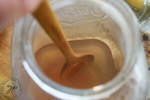 Stirring honey in hot water to dissolve it.