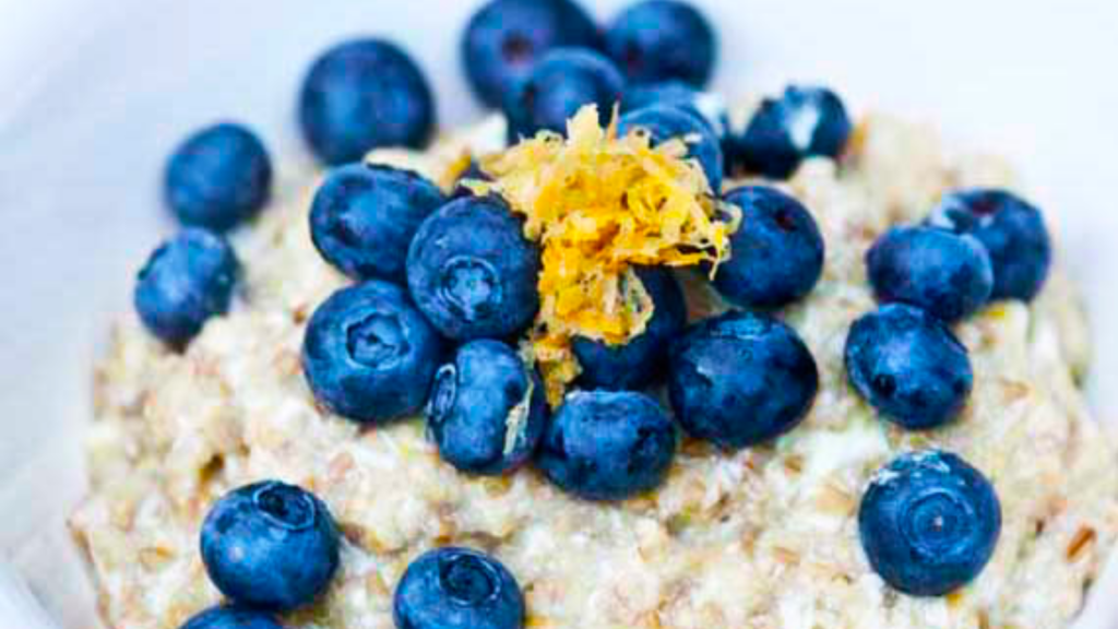A closeup of some lemon blueberry oatmeal, covered in fresh blueberries and lemon zest.