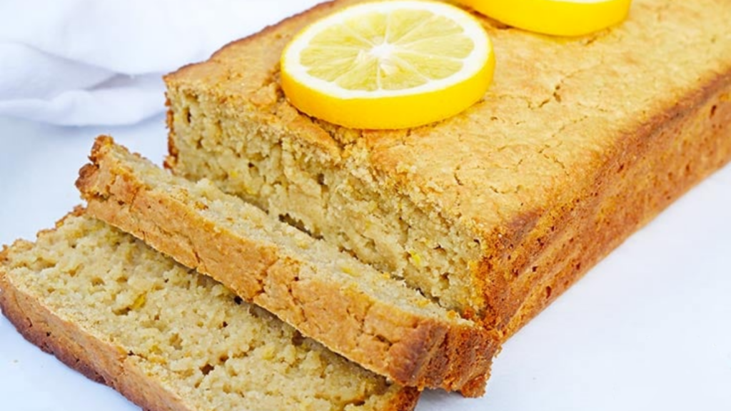 A partially cut loaf of lemon bread on a white surface.