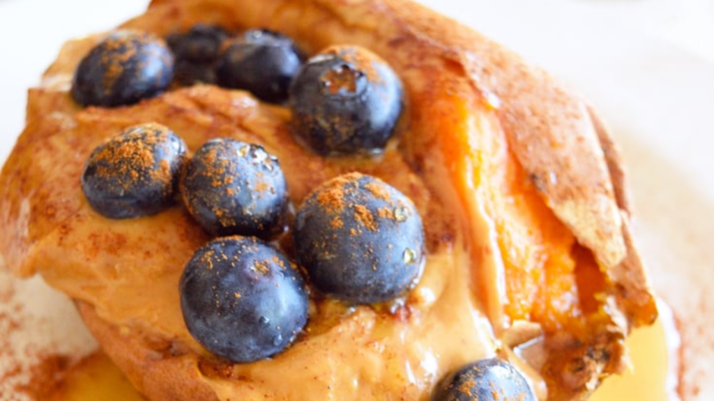 A closeup of a baked sweet potato stuffed with peanut butter, blueberries and cinnamon.
