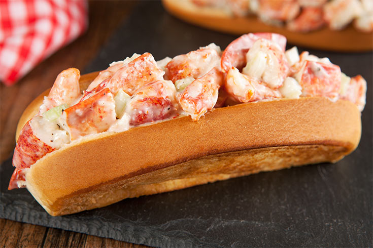 A lobster roll sitting on a stone surface.