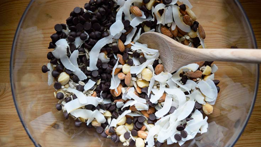 Low carb trail mix in a mixing bowl with a wooden spoon.