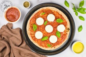 Fresh basil leaves added to the top of a pita pizza.