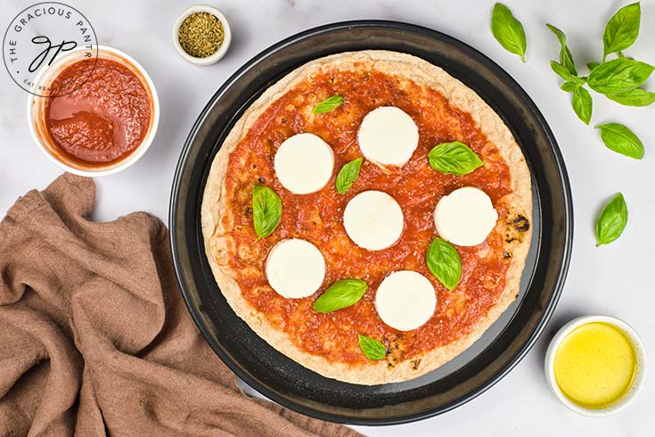 Fresh basil leaves added to the top of a pita crust.