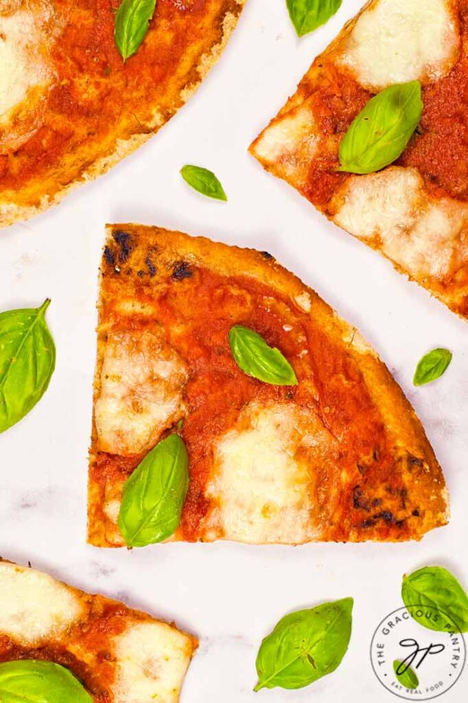 A closeup of a slice of Margherita Pizza with fresh basil leaves sprinkled over it.