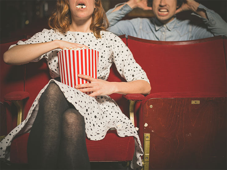 A woman loudly eating popcorn in a movie theater.