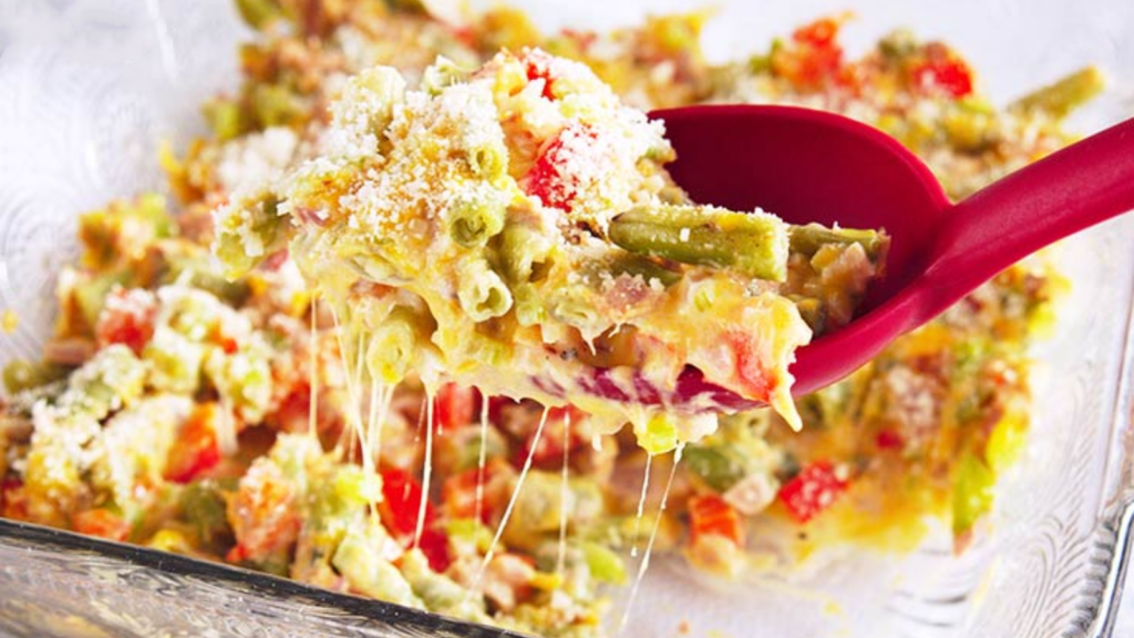 A spoon lifts some no noodle tuna casserole out of a casserole dish.