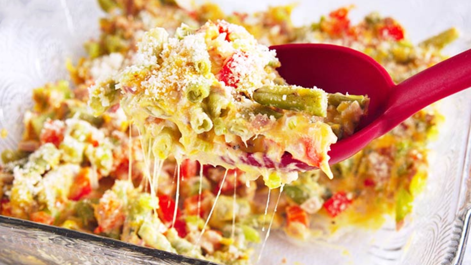 A spoon lifts some no noodle tuna casserole out of a casserole dish.