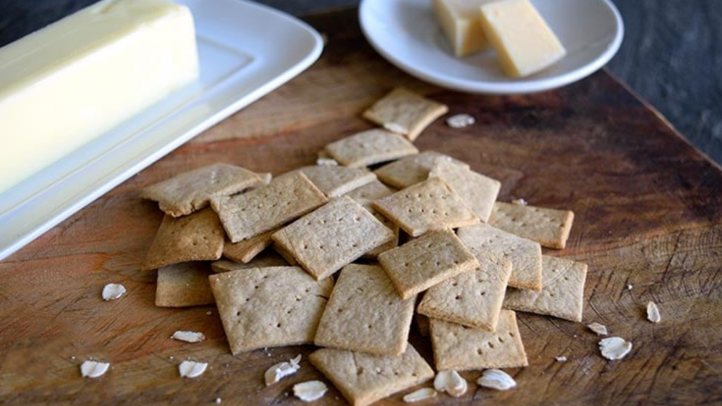 A pile of oat crackers on a cutting board.