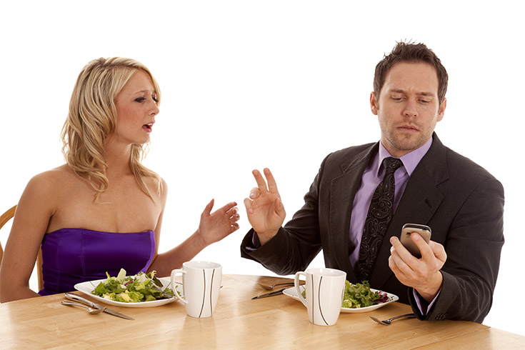 A man ignoring his date by looking at his phone.