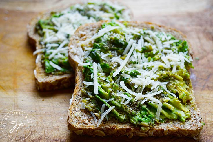 Two finished slices of Pesto Avocado Toast laying on a cutting board.