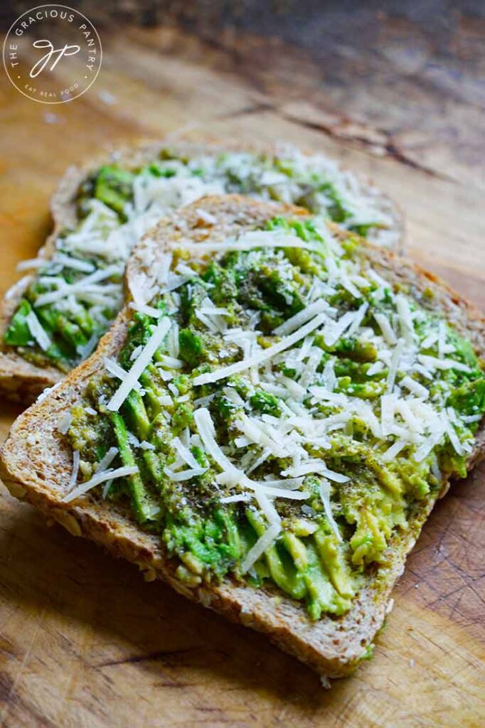 A front view of two slices of Pesto Avocado Toast laying on a cutting board, partially stacked.