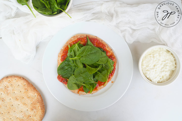 Topping the pizza with spinach leaves.