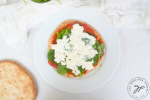 Topping the Pita Pizza with cottage cheese.