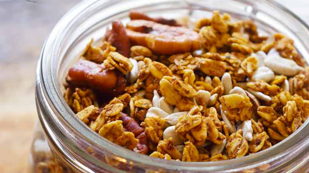 An up close shot of an open glass jar filled with pumpkin granola.