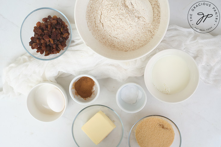 Raisin Scones Recipe ingredients in individual bowl on a white background.