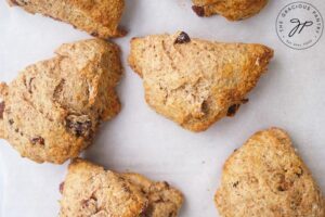 Just-baked Raisin Scones laying on a parchment-lined baking pan.