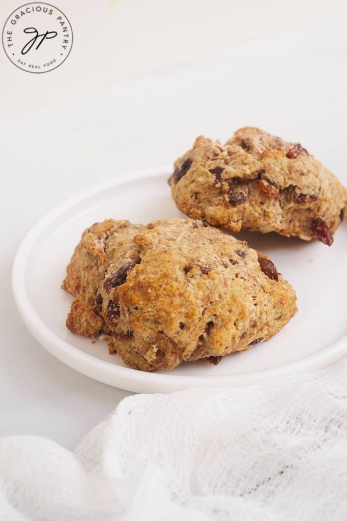 Two Raisin Scones on a white plate.