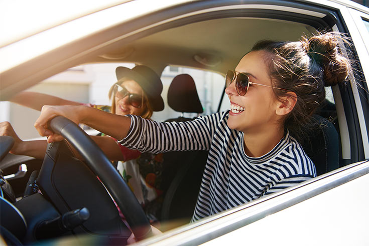 Two young women driving in a car.