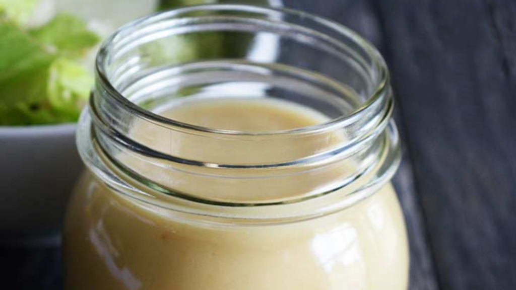 An open jar filled with roasted garlic vinaigrette.