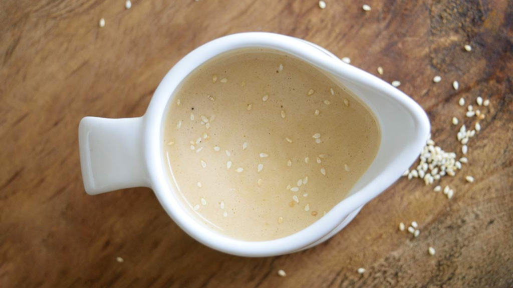 An overhead view looking into a white pitcher filled with sesame vinaigrette dressing.