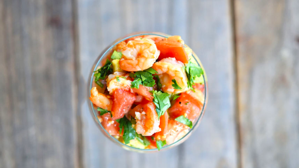 An overhead view looking down into a glass filled with shrimp campachana.