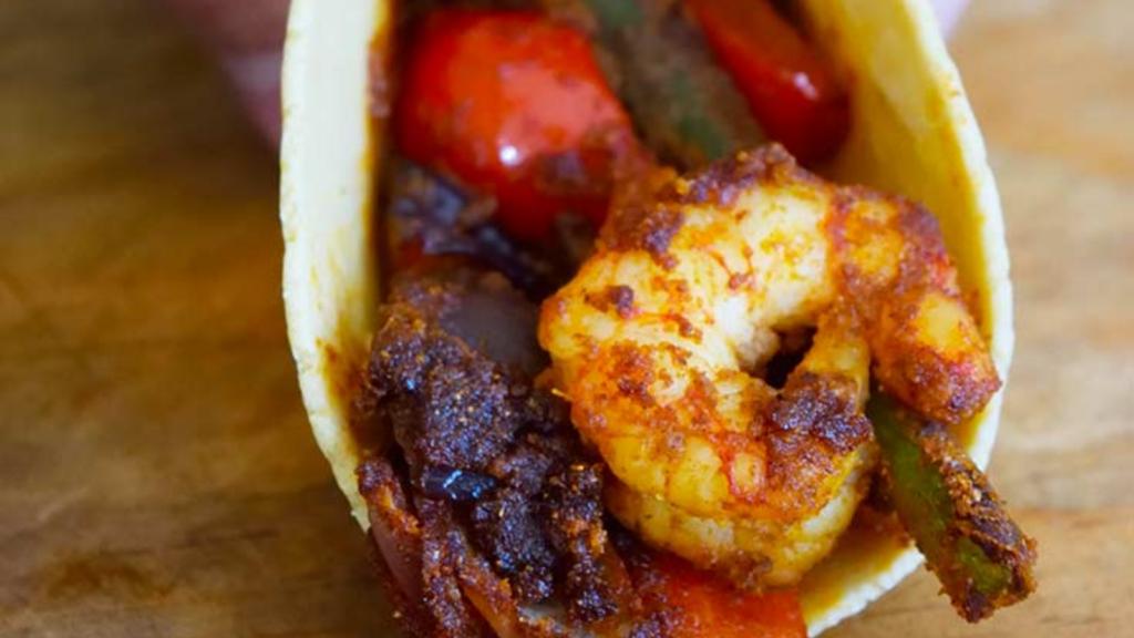 A closeup of a shrimp fajita in a corn tortilla.