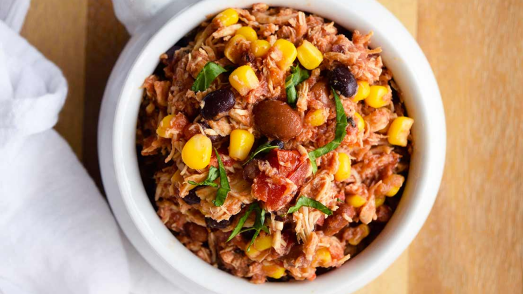 An overhead view of a white crock filled with slow cooker southwestern chicken.