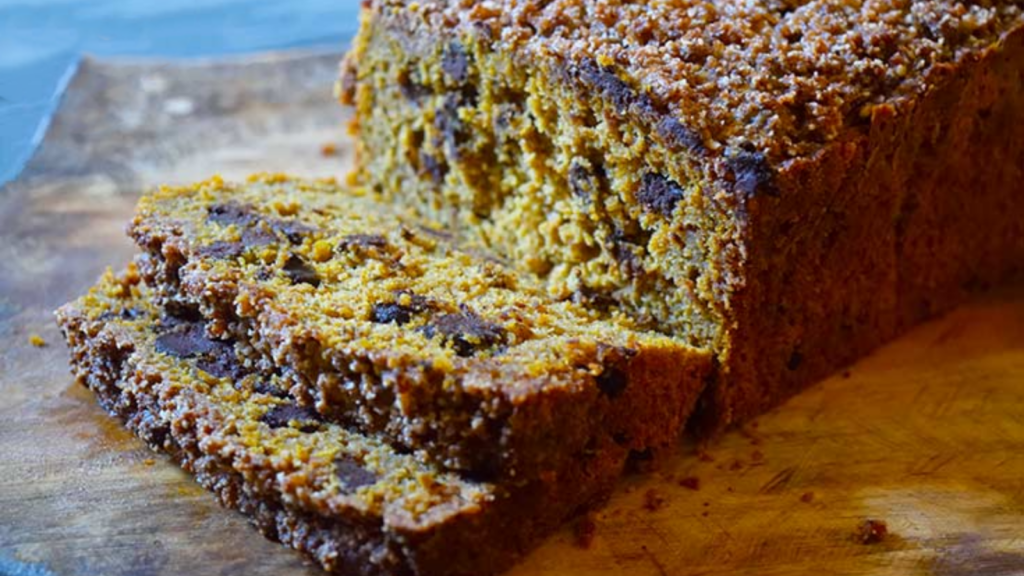 Two slices of snickerdoodle pumpkin bread cut from a loaf on a cutting board.