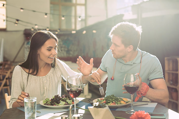 A woman taking food from a man's plate. He looks upset.