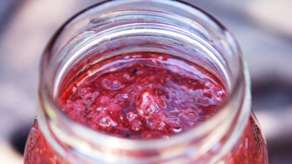 A view over the edge of an open jar that is full of strawberry chia seed jam.