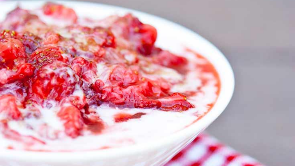 A white bowl holds a serving of strawberry fool.