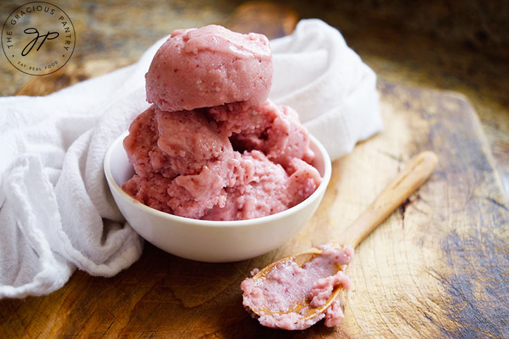 A small white bowl holds several scoops of Strawberry N'ice Cream. A spoon rests in front of the bowl with a bit of N'ice cream on it.