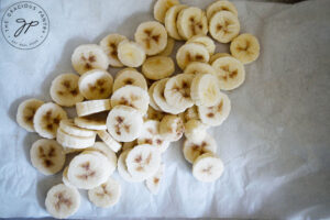 Slices, frozen bananas on parchment paper.