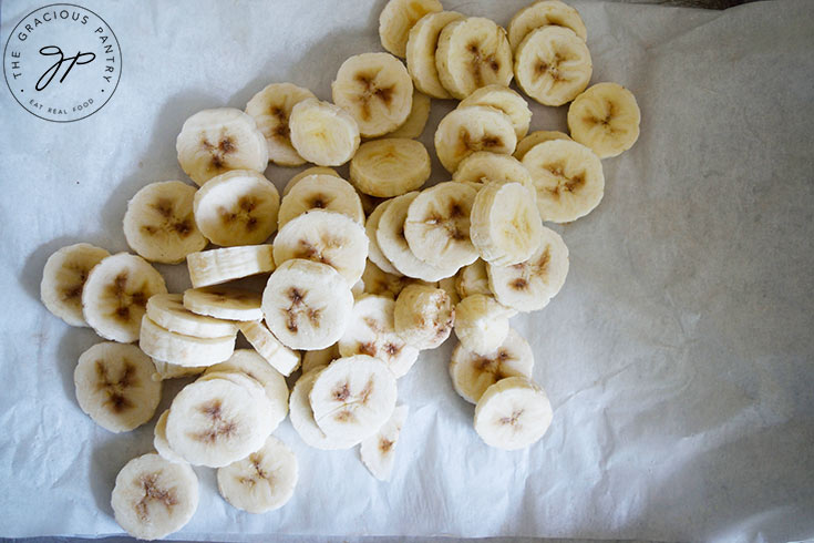 Slices, frozen bananas on parchment paper.