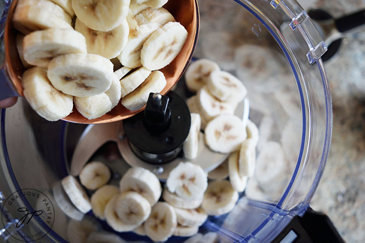 Slice frozen bananas being put into a food processor.