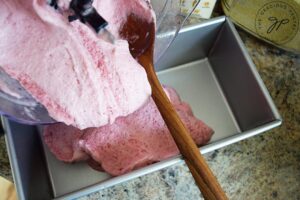 Scraping the Strawberry N'ice Cream our of the food processor bowl and into a loaf pan.