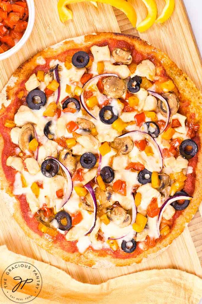 An overhead view of a just-made Supreme Pizza on a cutting board.