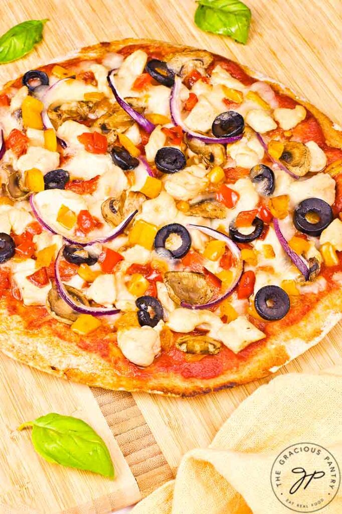 A whole Supreme Pita Pizza on a cutting board.