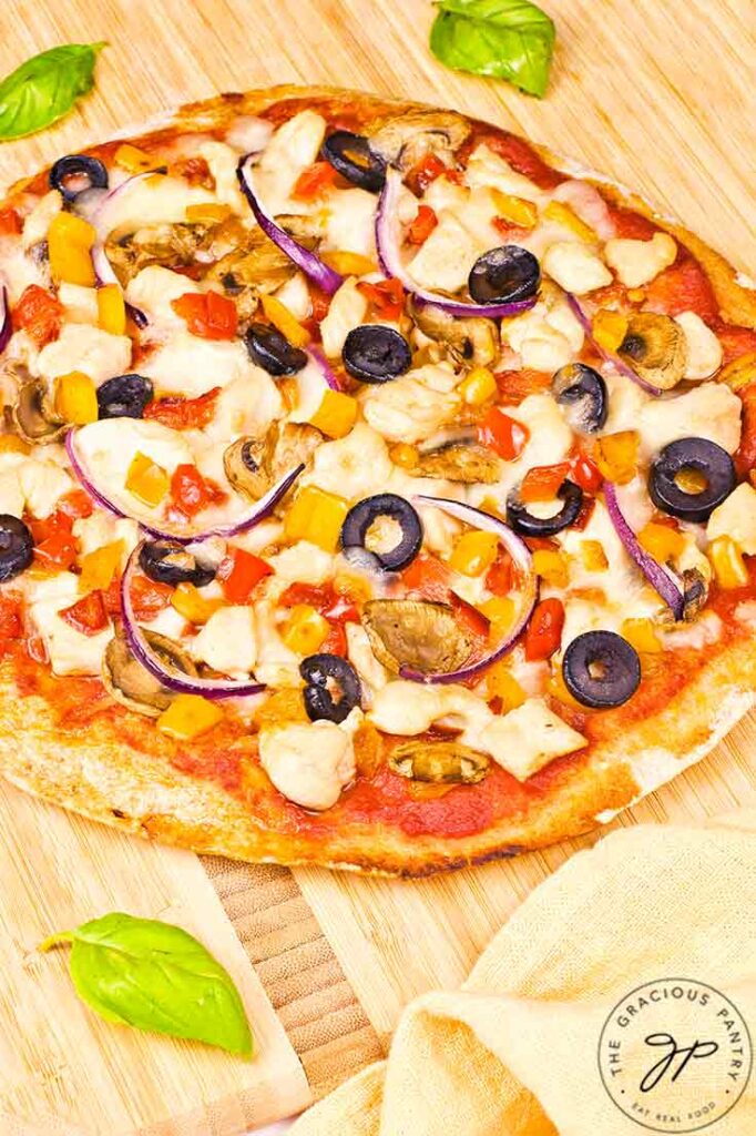 A whole Supreme Pita Pizza on a cutting board.