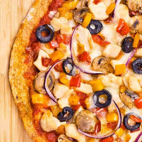 Looking down on a Supreme Pizza laying on a cutting board.