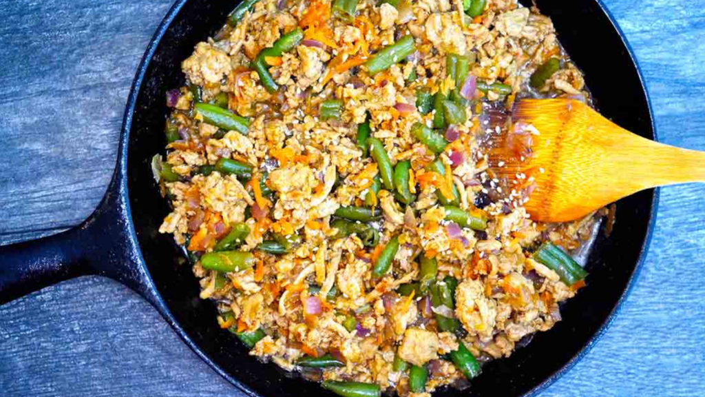 An overhead view of a cast iron skillet filled with teriyaki turkey skillet..