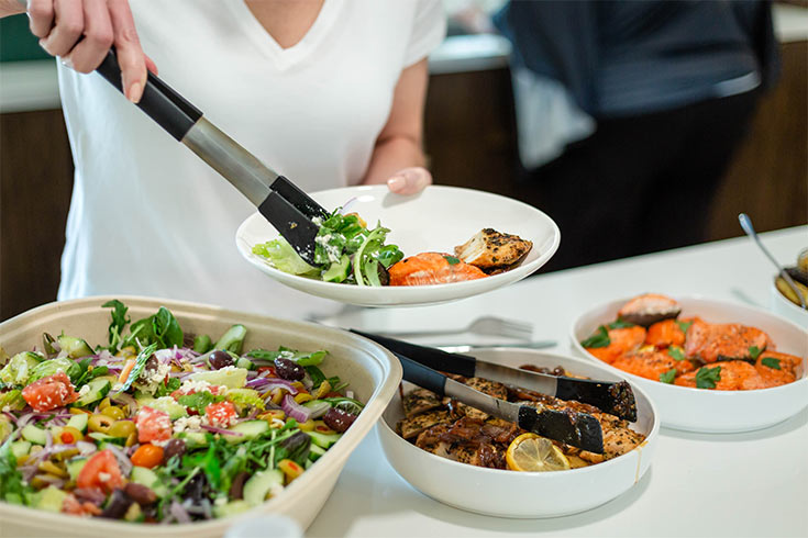 A woman serving herself at a buffet.