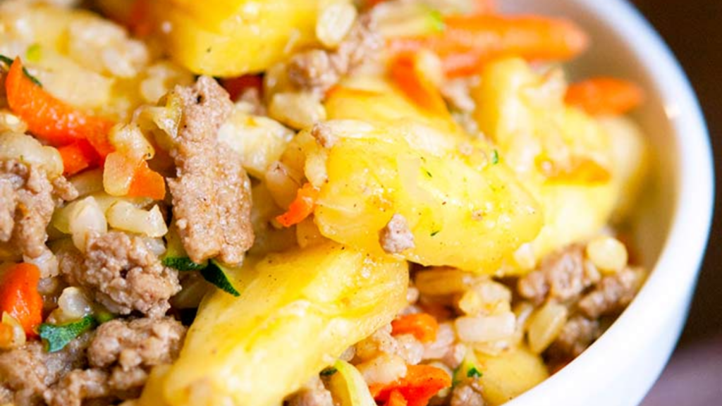 A closeup of a white bowl filled with turkey pineapple rice.