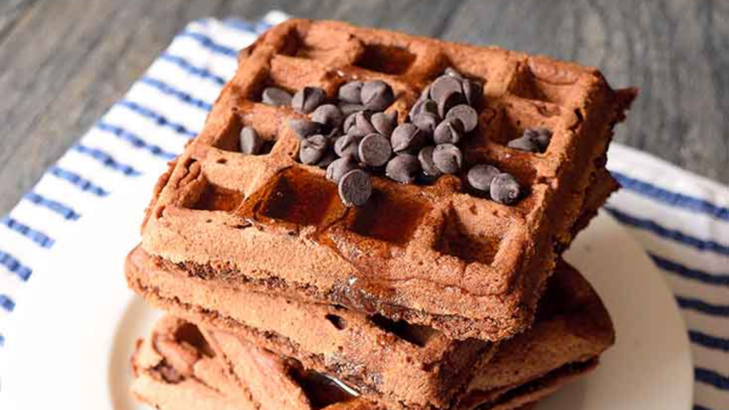 A stack of vegan brownie waffles with chocolate chips on top.